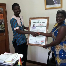 Joseph Amartey of Tourism Society of Ghana presents a citation to Akua.